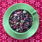 green teacup full of fruits and flowers on a pink flower backdrop