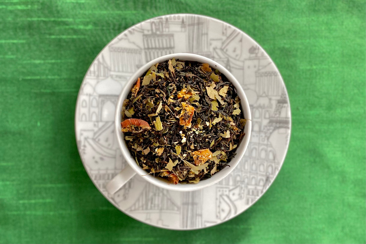 Black and white teacup full of green tea, fruit and herbs