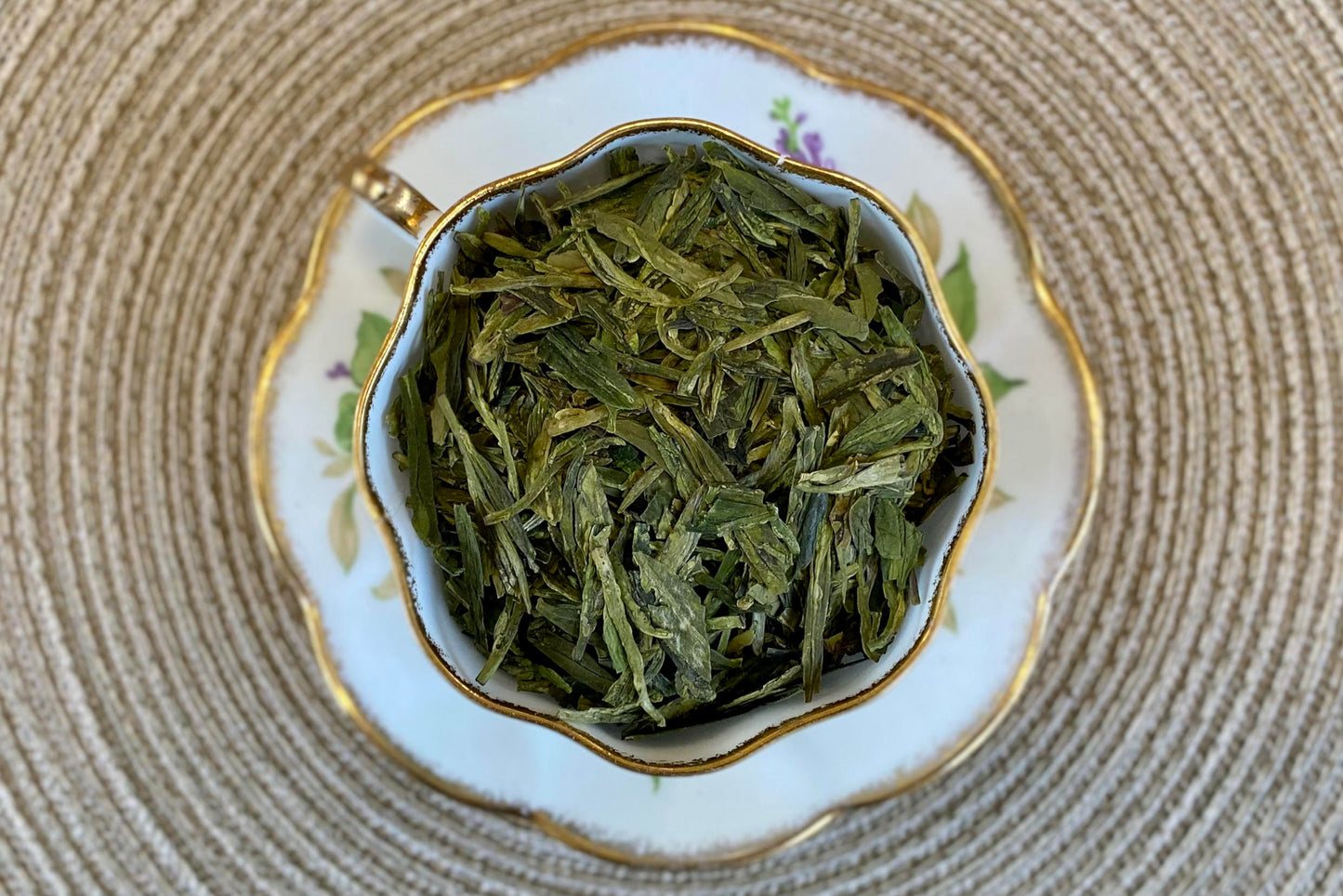 Teacup full of flat green tea leaves