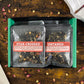 Two tea packages labeled 'Star-Crossed' and 'Untamed' on a wooden surface with flowers.