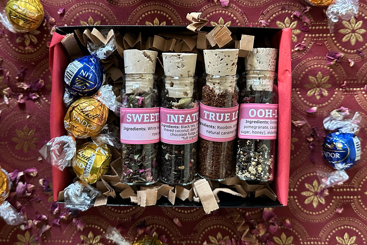 Open box of Love Potions, showing four glass vials of tea and three Lindt chocolate truffles