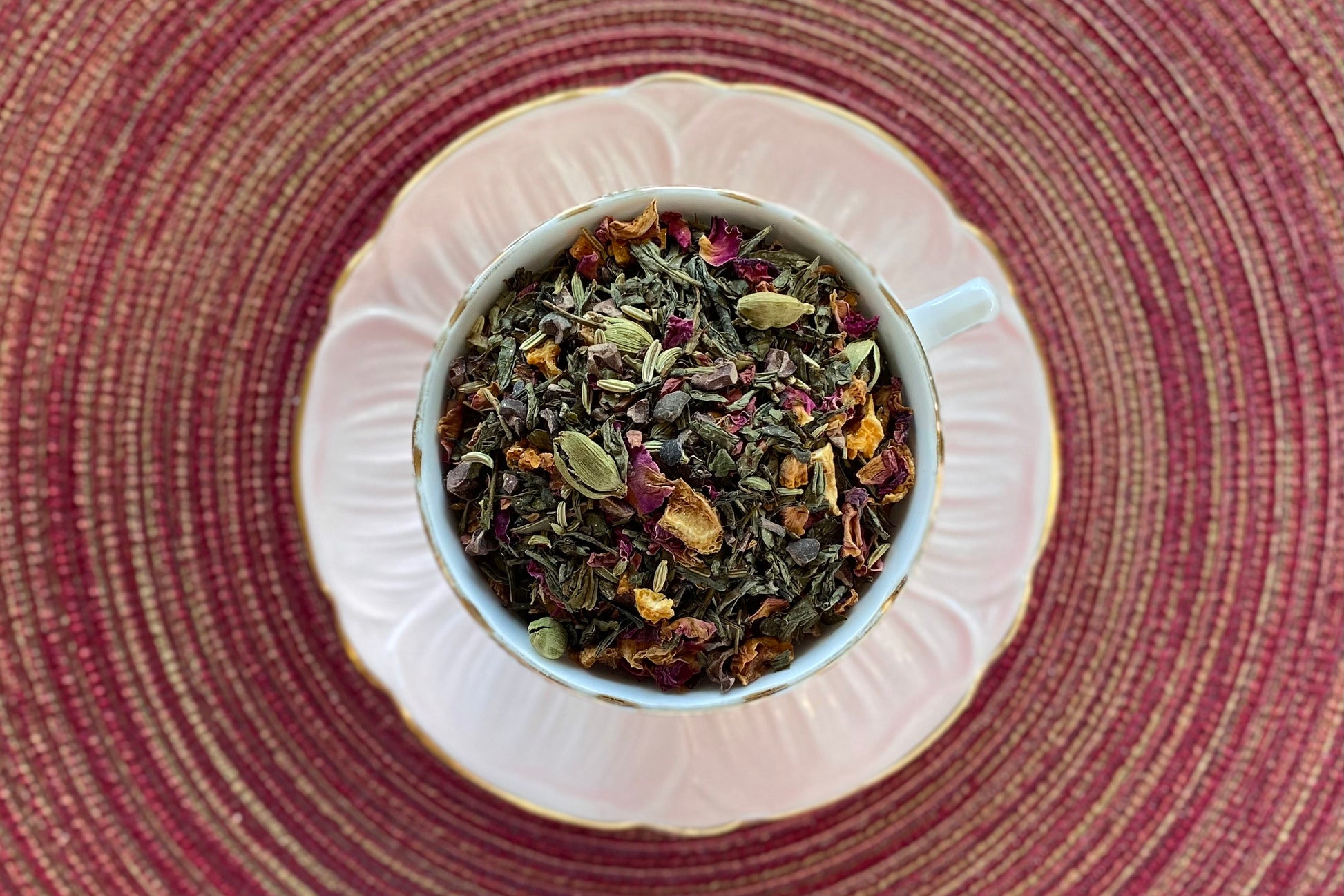 Pink teacup full of green tea, spices and citrus