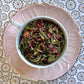 teacup full of white tea with rose petals and gold glitter