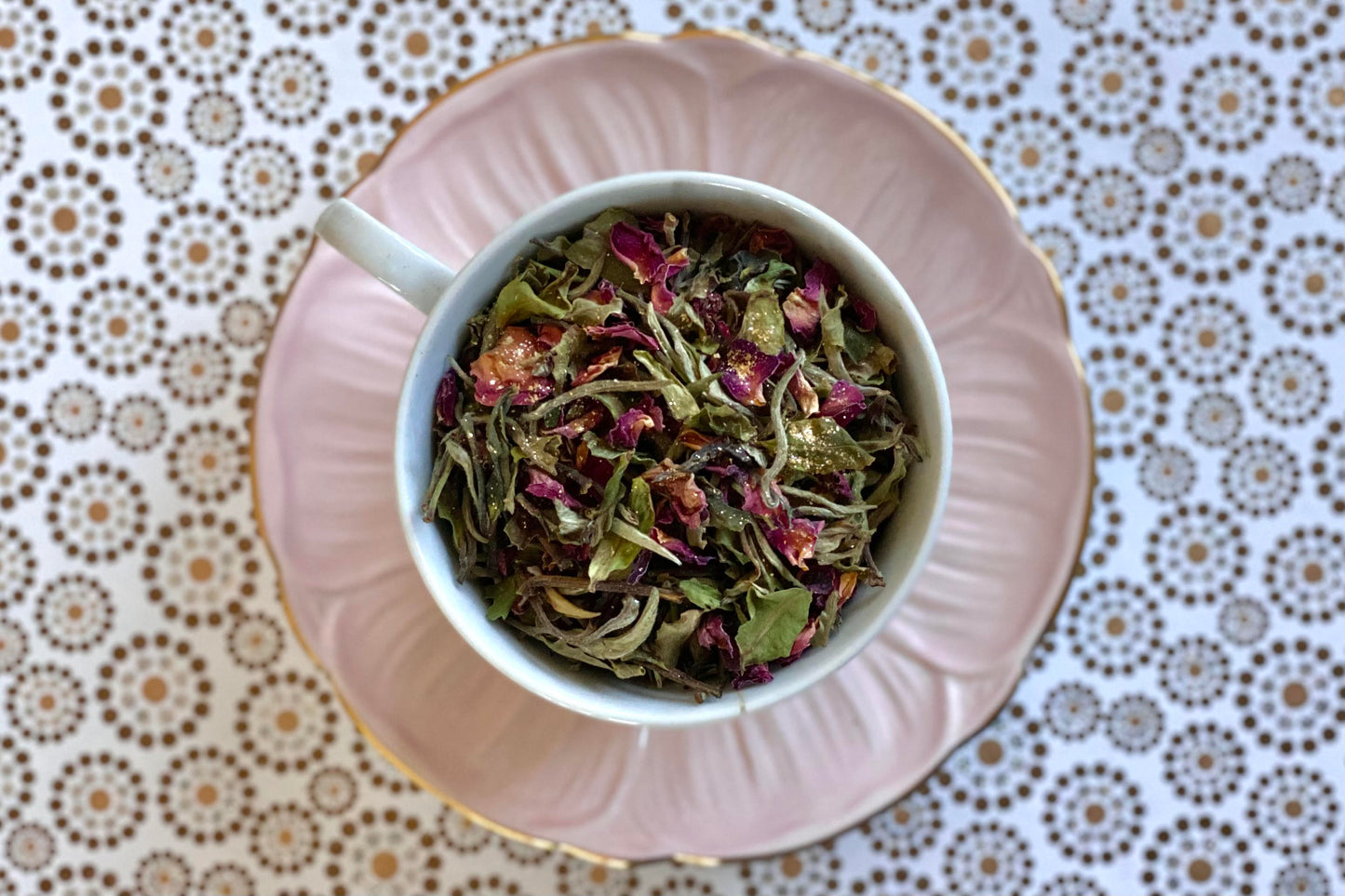 teacup full of white tea with rose petals and gold glitter