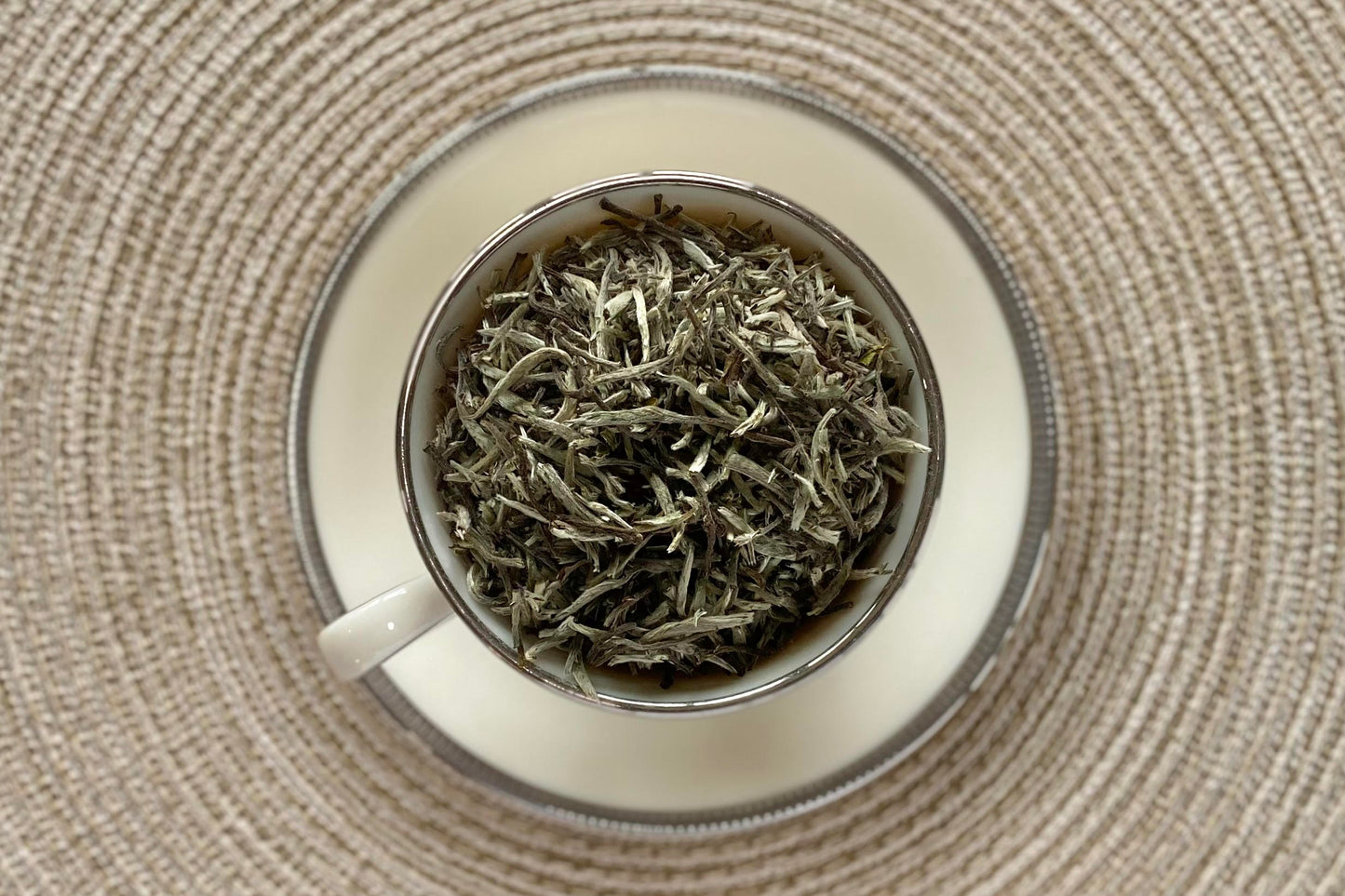 White teacup full of fuzzy silver needle white tea