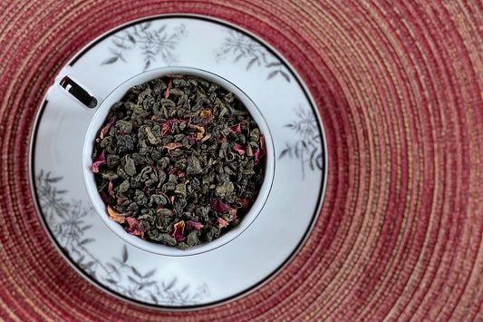 teacup full of rolled green tea and rose petal
