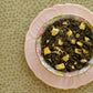 teacup full of rolled green leaves and peach pieces